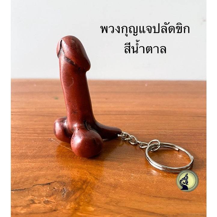 One-Sake.com Thai lucky keychain shaped like a carved wooden symbolic amulet on wooden surface