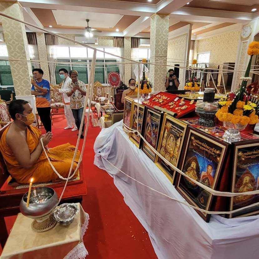Ceremony with monks and offerings featuring the Thai Phra Pidta amulet for protection on display