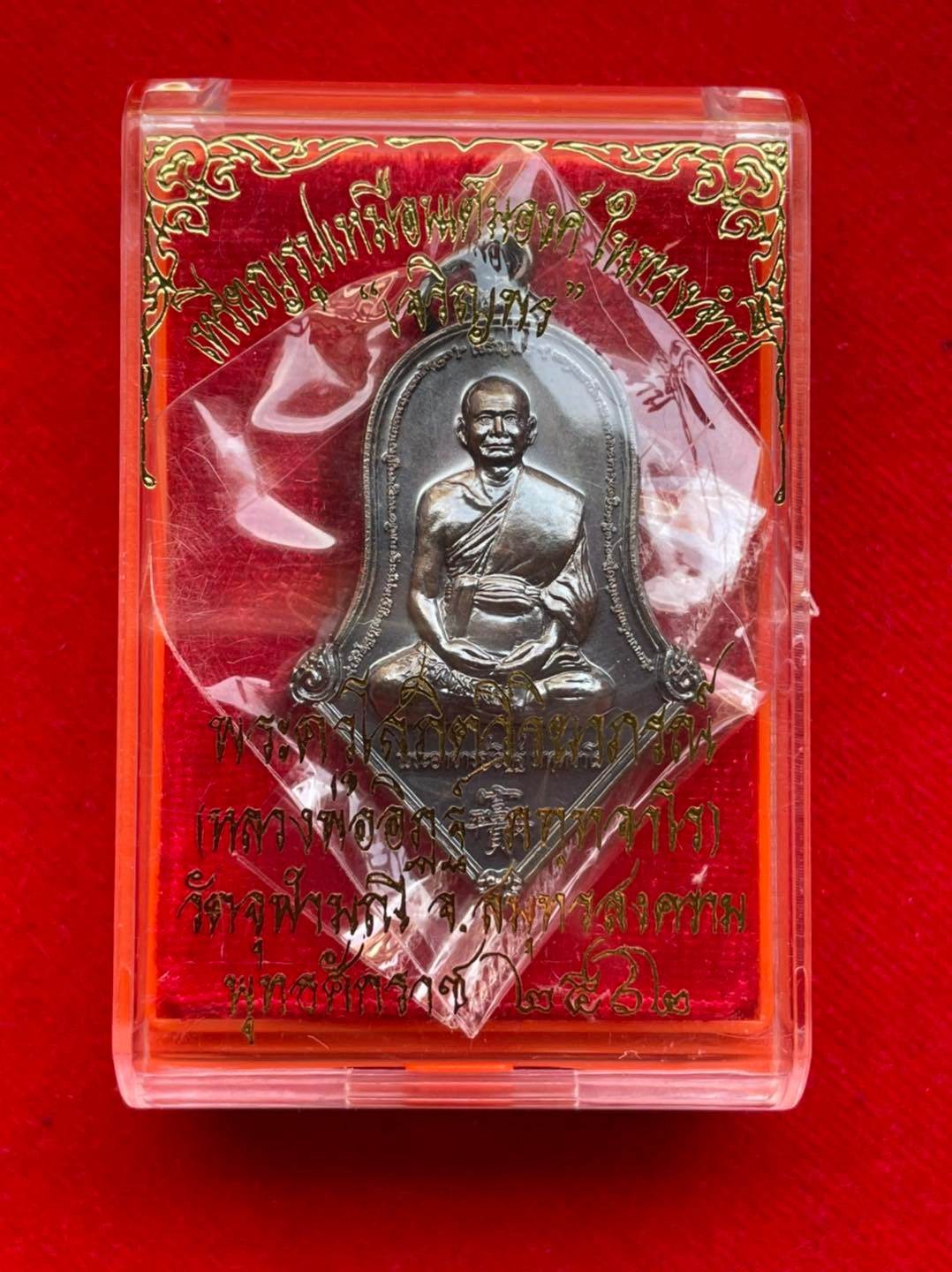 Thai prosperity amulet for sale in protective packaging featuring a monk medallion for good fortune