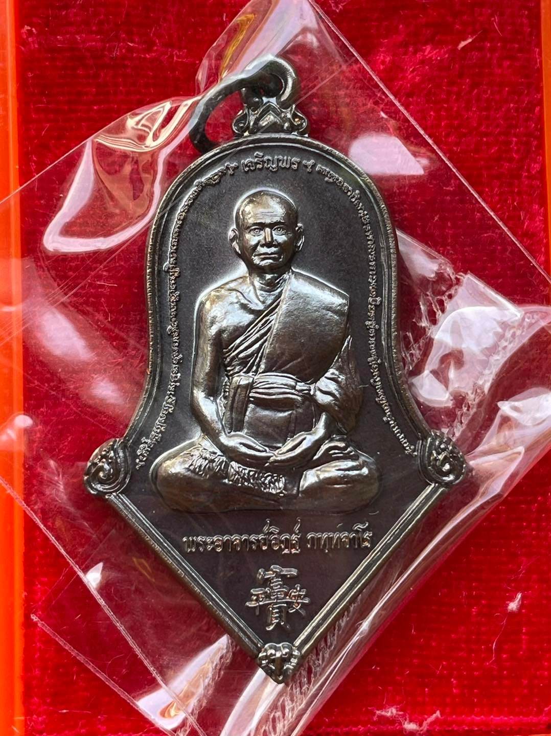 Thai prosperity amulet for sale featuring a seated monk design with intricate details