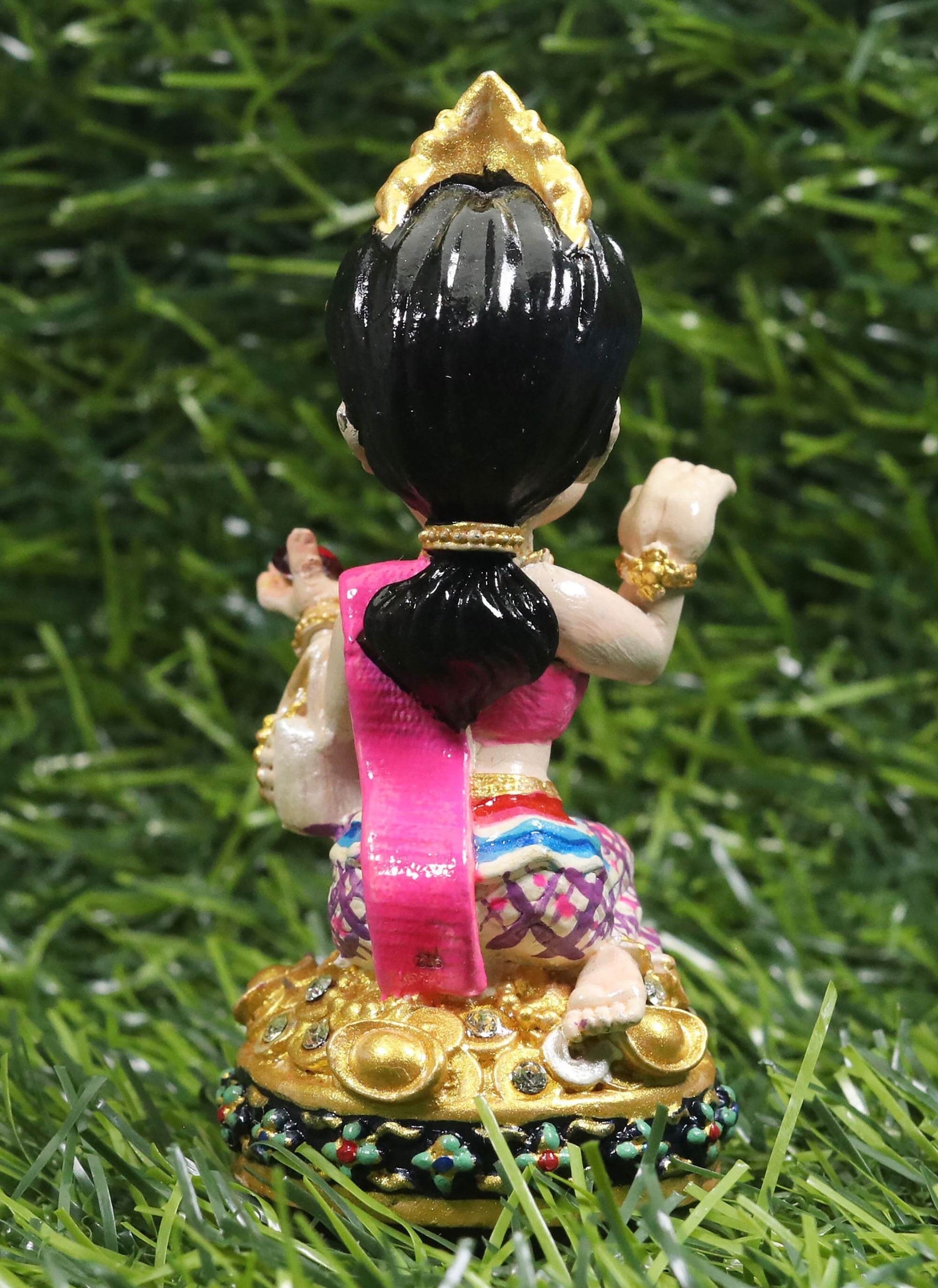 Thai prosperity figurine for shop decor featuring traditional attire and gold accents on green grass background