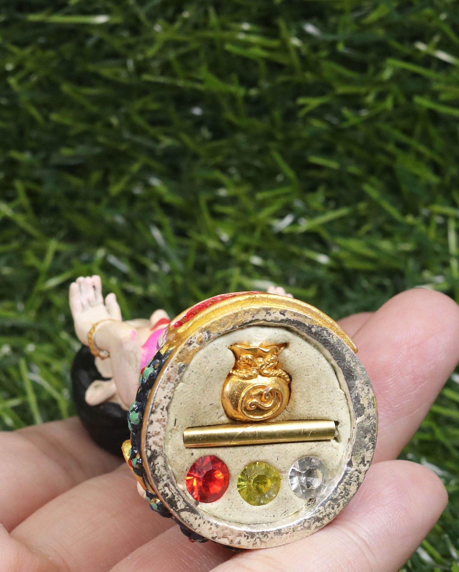 Thai prosperity figurine for shop decor held in hand showing detailed base with gold and colorful accents