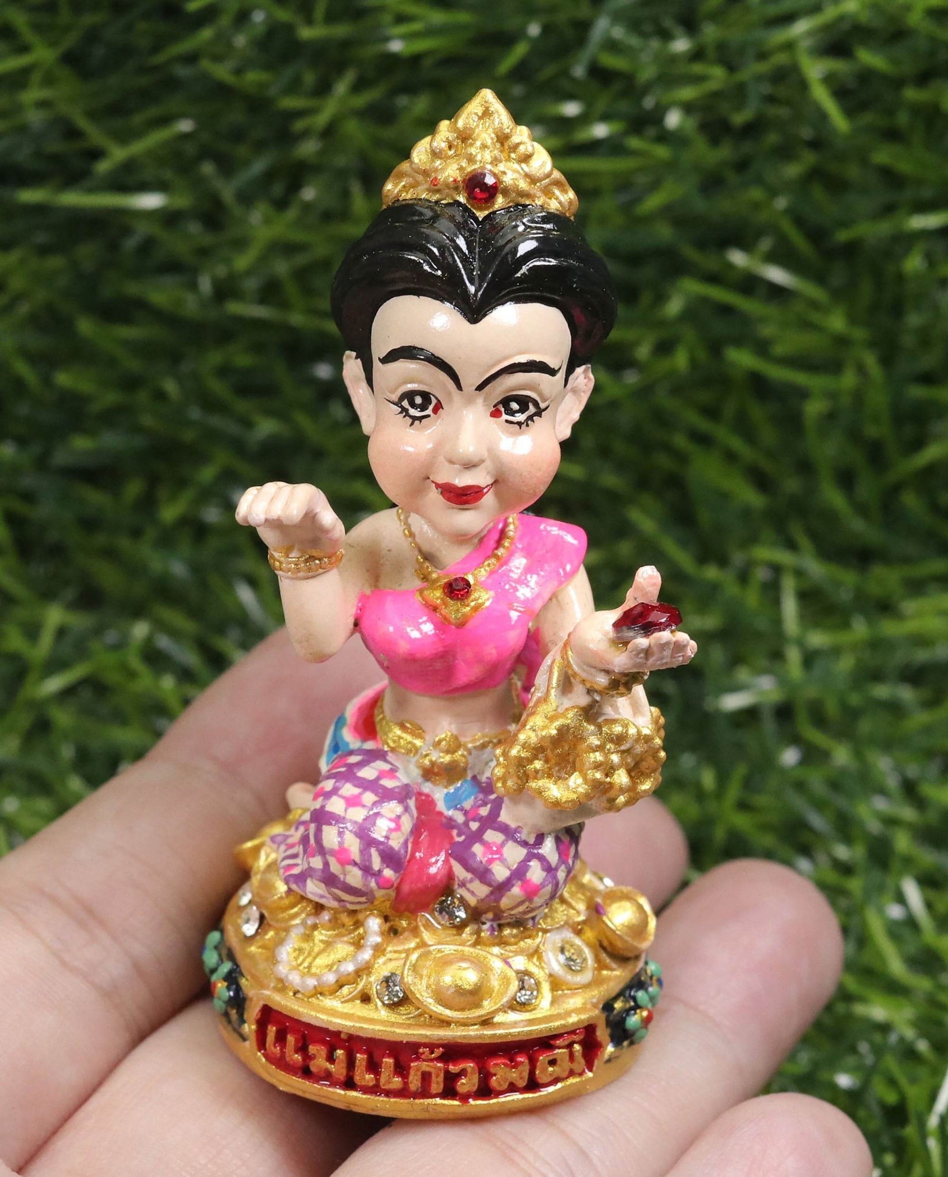 Thai prosperity figurine for shop decor with traditional attire and gold accents held in hand