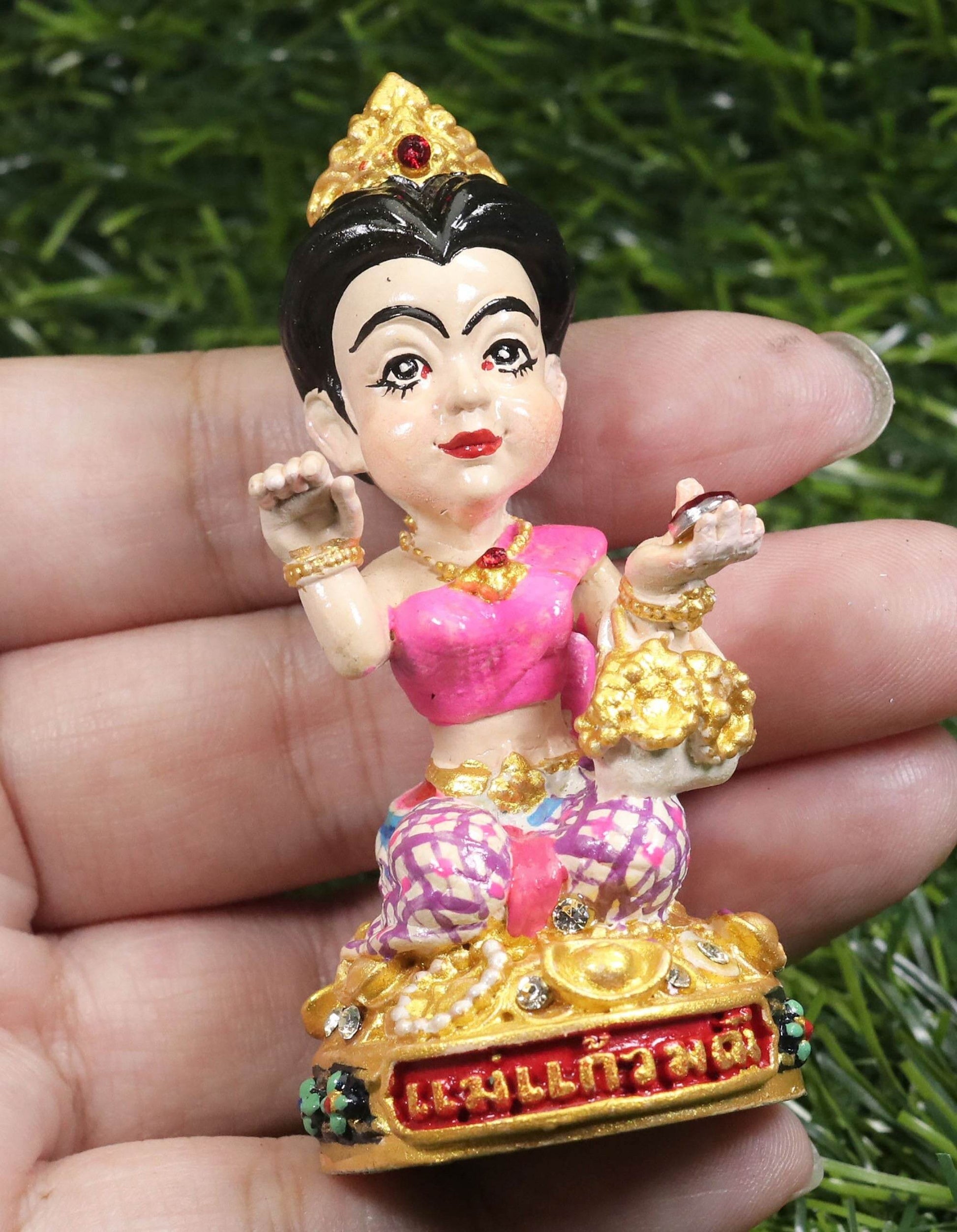 Thai prosperity figurine for shop decor with traditional attire and golden accents held in hand