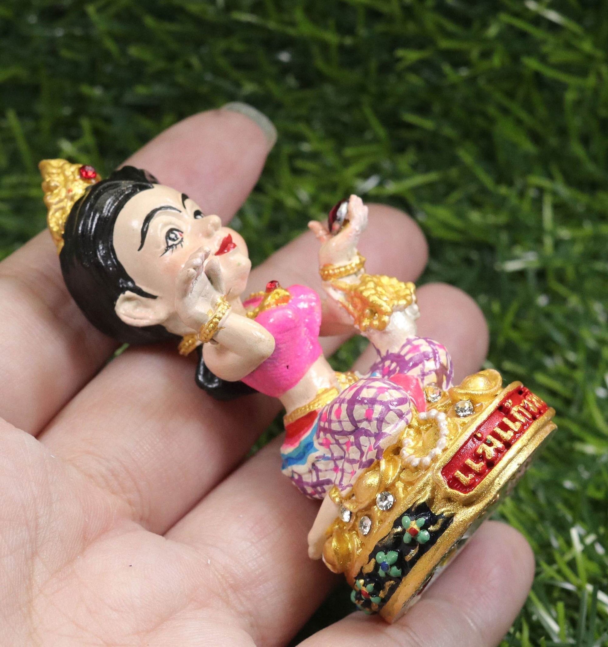 Thai prosperity figurine for shop decor held in hand featuring traditional attire and gold accents