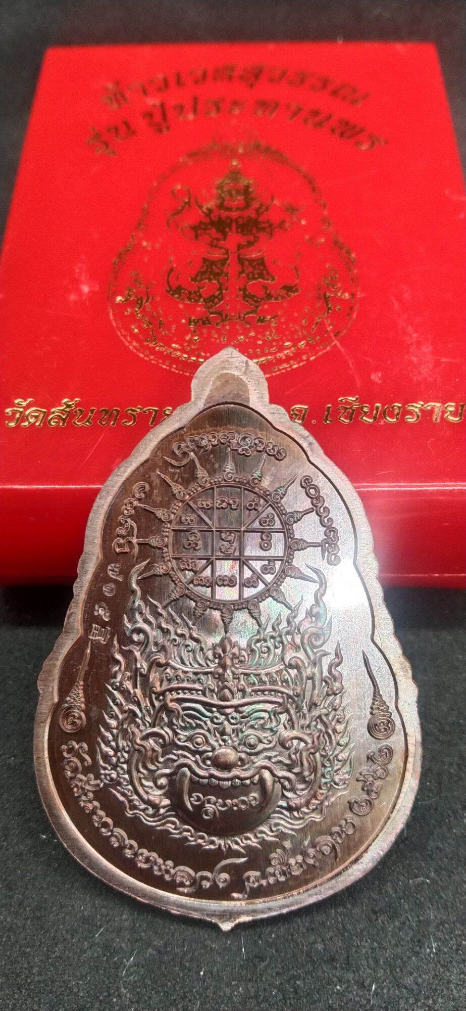 Thai protective talisman for wealth with intricate design and sacred inscriptions on metal pendant