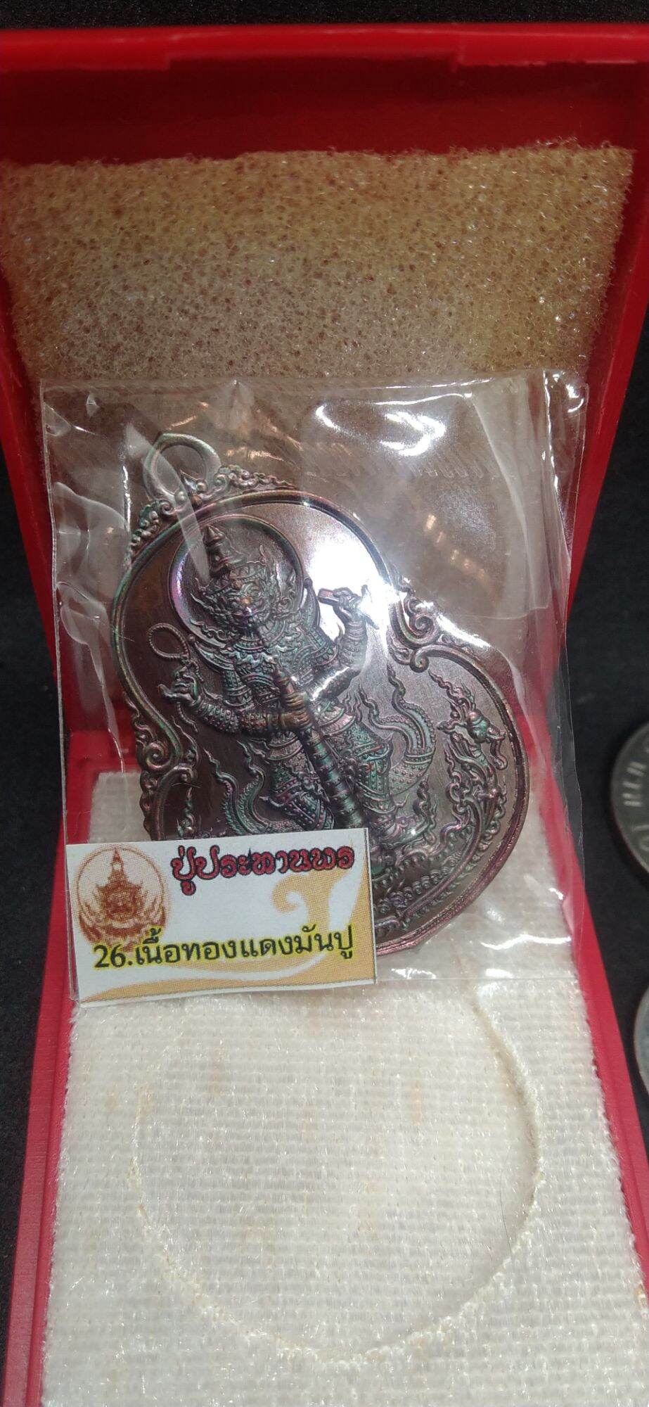 Thai protective talisman for wealth in silver packaging from Thai Blessing Co displayed inside a red box