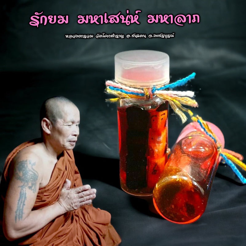 Thai Rak Yom twin child spirit amulet bottles with colorful string next to a praying monk