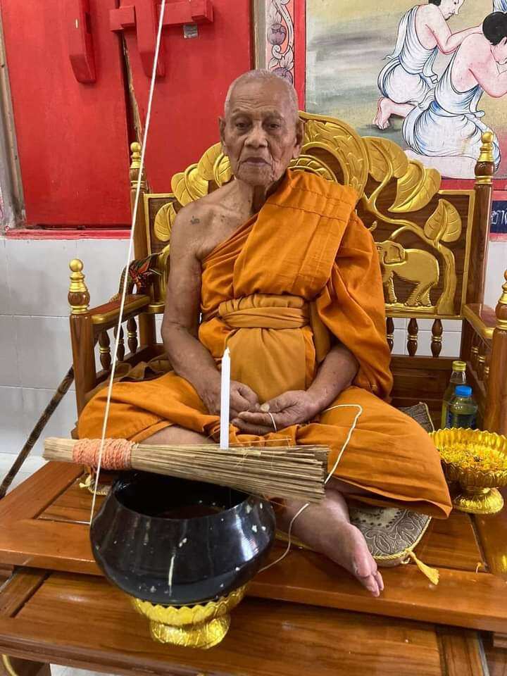 Thai monk blessing Ruesi Hermit Amulet Wat Khao Or seated on ornate chair with alms bowl and candle