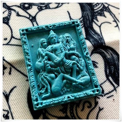 Thai seduction charm talisman featuring intricate carvings of deities and figures in a turquoise finish