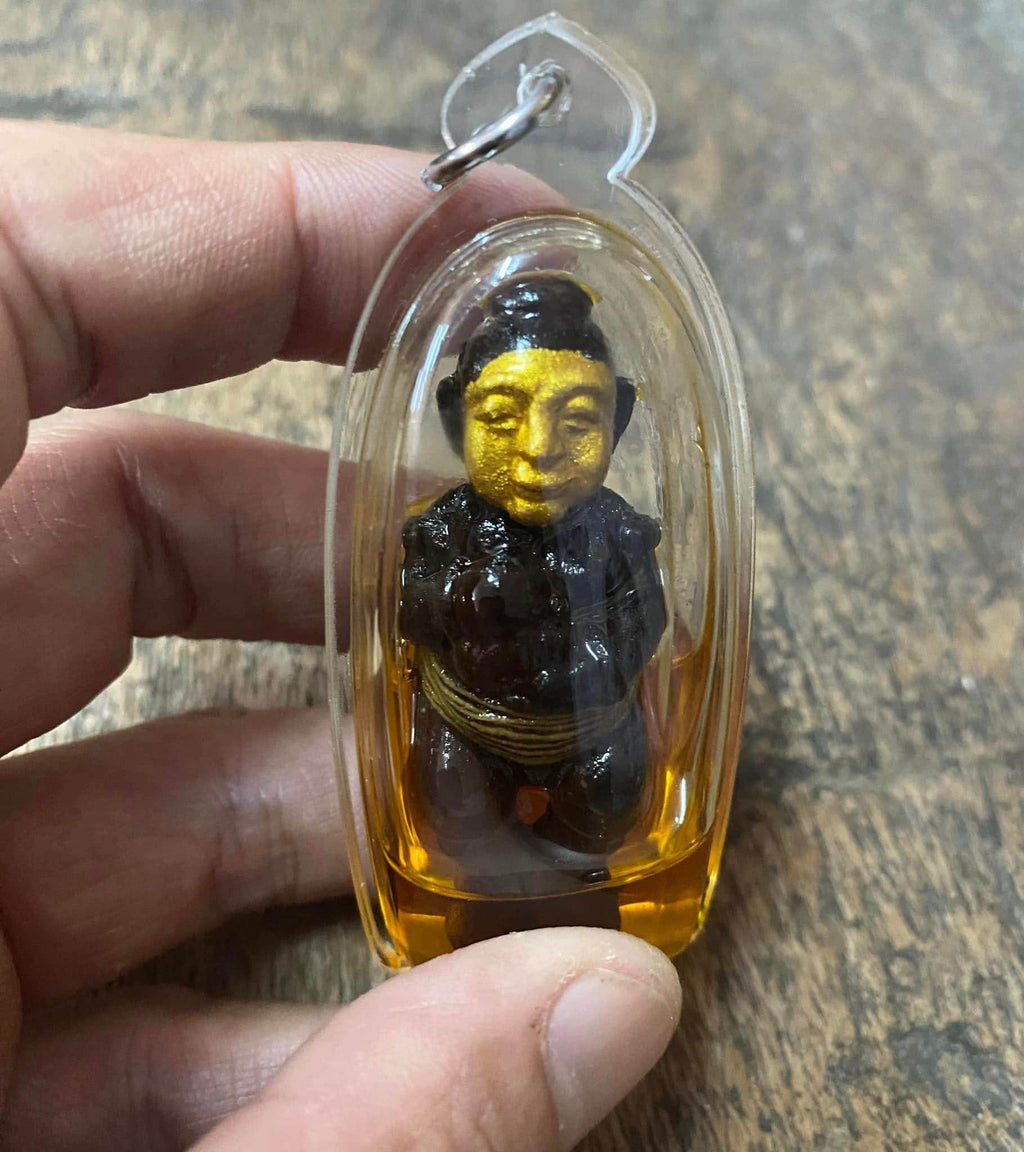 Handheld thai spirit doll for wealth and protection encased in clear plastic for good fortune