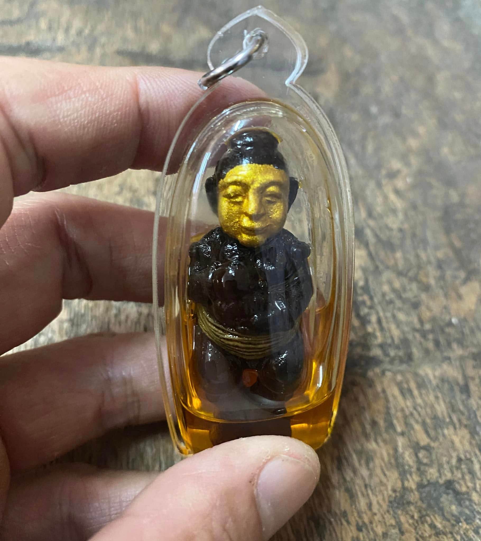 Handheld thai spirit doll for wealth and protection encased in clear plastic for good fortune