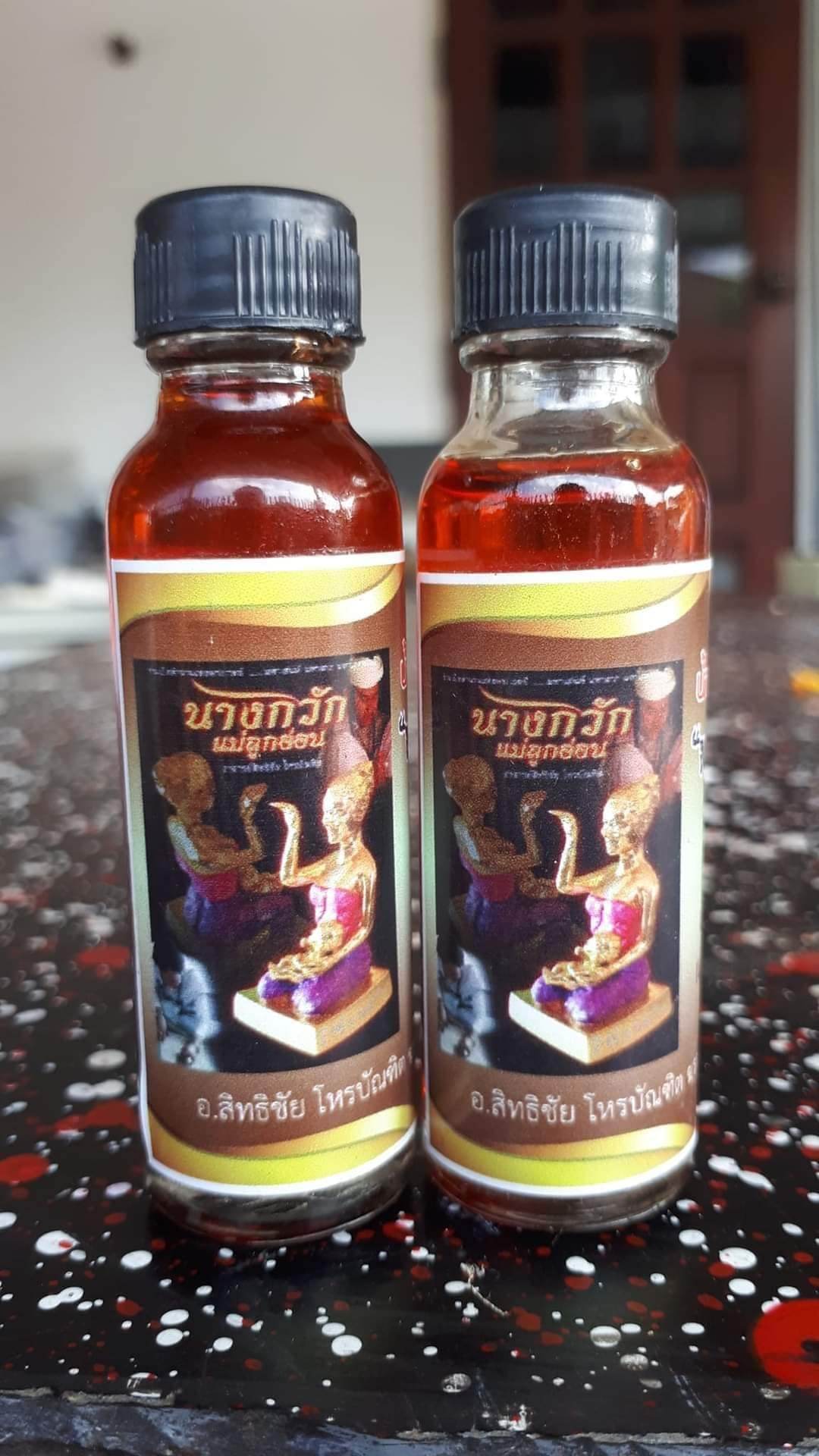 Thai spiritual wealth amulet oil bottles by Thai Blessing Co with traditional deity illustration