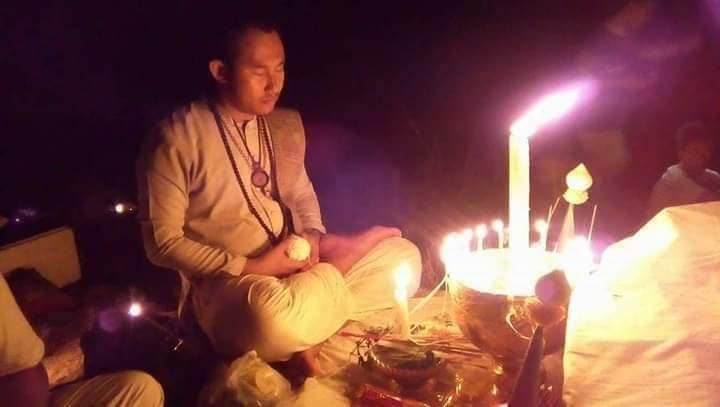 Man meditating by candlelight during a Thai spiritual wealth amulet blessing ceremony