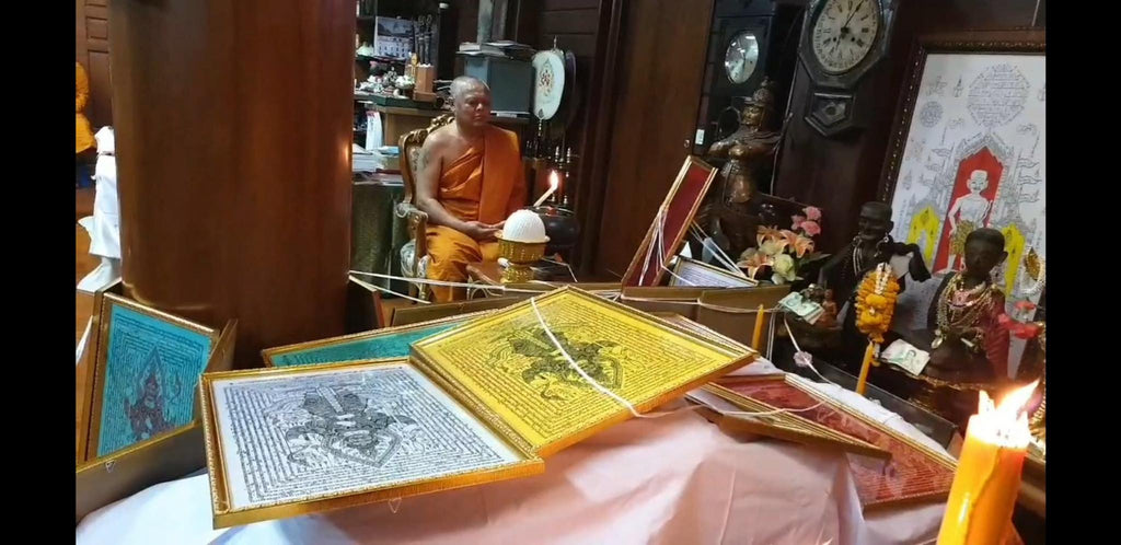 Thao Wessuwan yantra cloth framed talismans displayed on a Thai altar with a monk performing a blessing ritual