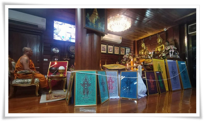 Thao Wessuwan yantra cloth displayed among framed sacred cloths in Thai shrine with monk and Buddha statues