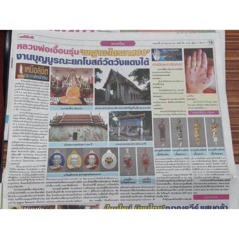 Thai newspaper article showing monk temple photos and multiple amulet closeups including Tiger Takrud amulet for status elevation