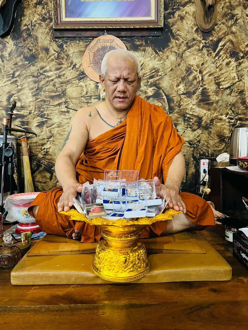 Thai monk blessing Hoon Payon amulet dolls Thailand on golden tray in temple setting for consecration