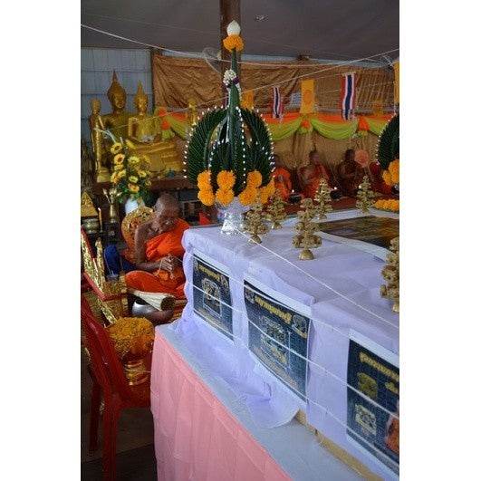 Buddhist temple altar setup featuring a Thai wealth pig amulet surrounded by traditional offerings