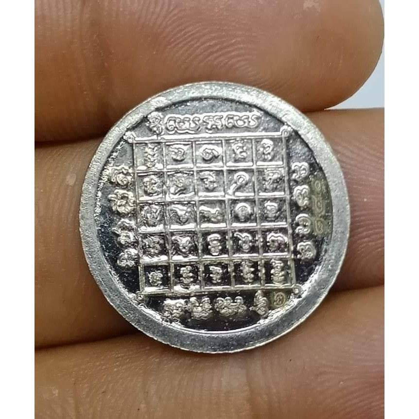Close-up of a Thai zodiac amulet featuring traditional designs and zodiac symbols in a coin format