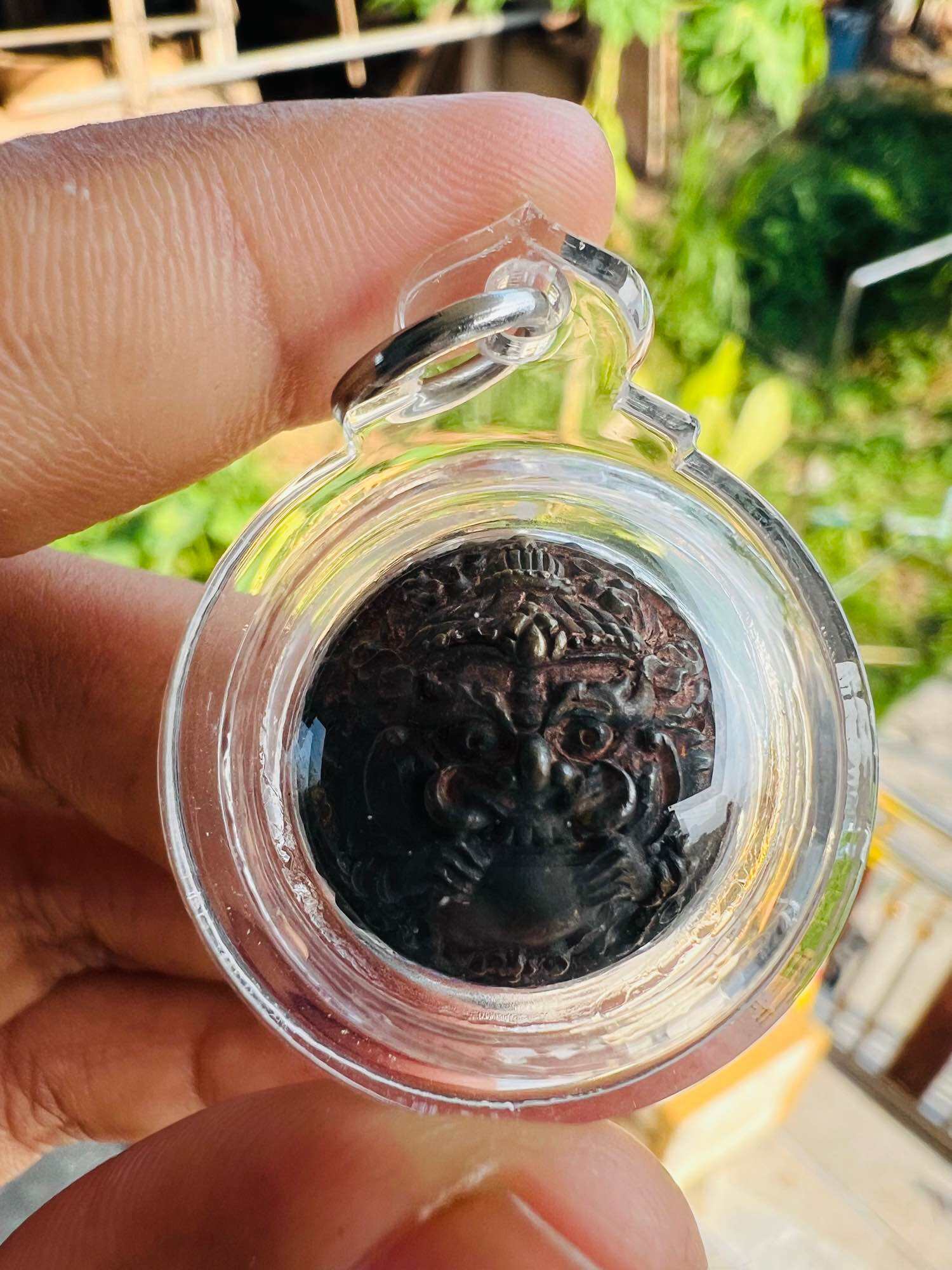 Thai Blessing Co pendant showing a carved dark amulet face in clear case ancient Thai talisman first edition for collectors