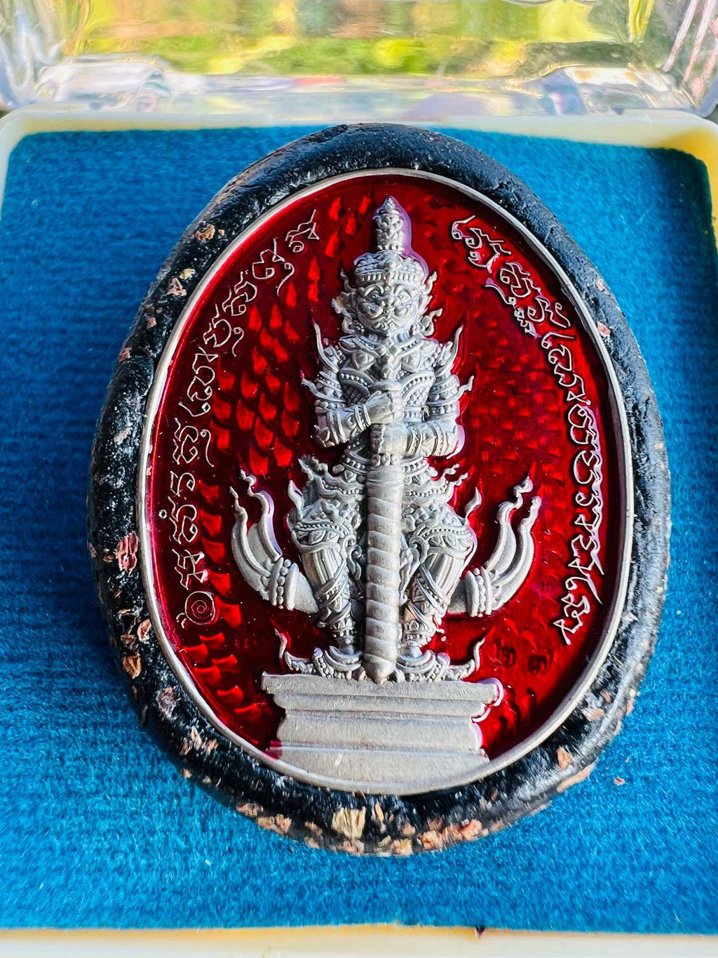 Bia Gae Lord Vaisravana amulet red oval with silver deity relief Thai script black frame on blue velvet