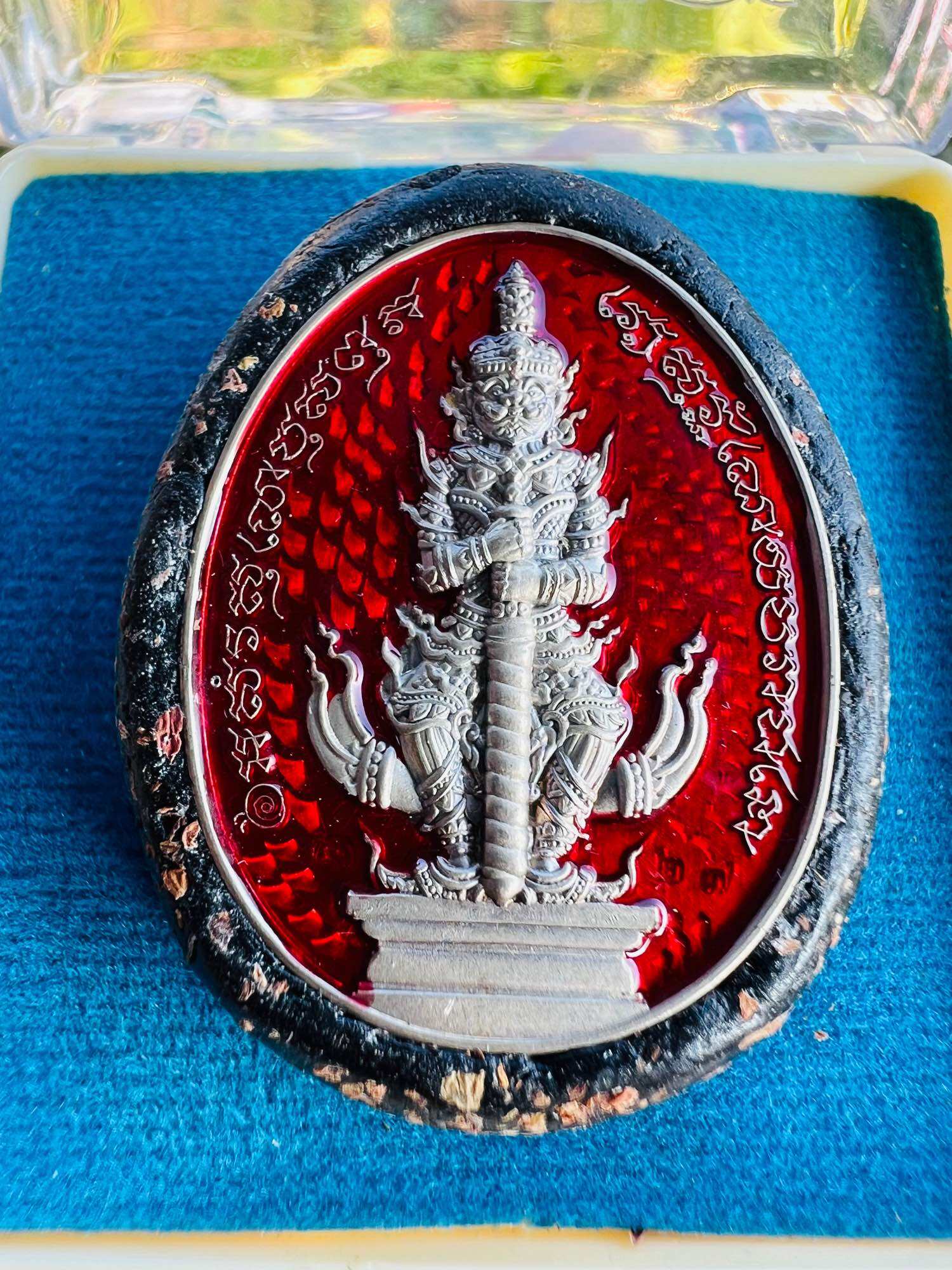 Bia Gae Lord Vaisravana amulet red oval with silver deity relief Thai script black frame on blue velvet