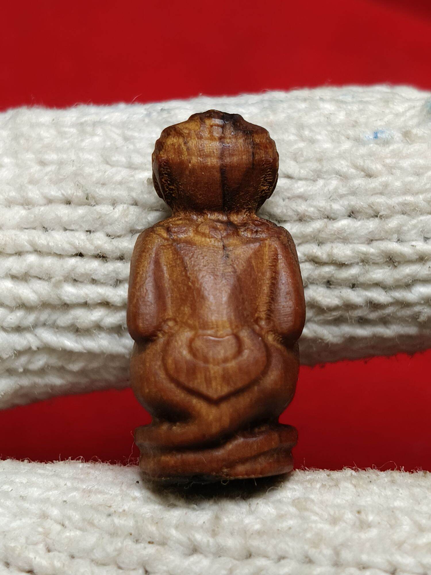 Thai Blessing Co wooden Hanuman monkey god amulet pendant carved figure back view on white glove red background