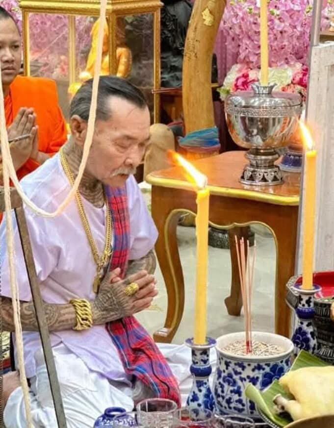 Hanuman monkey god amulet pendant on gold chain worn by Thai devotee at altar during ceremony