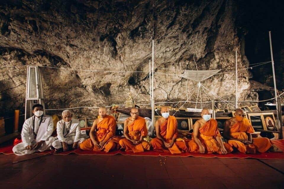 Kwai Thanhu Full Moon Edition Amulet blessing ceremony with seated Buddhist monks in a cave