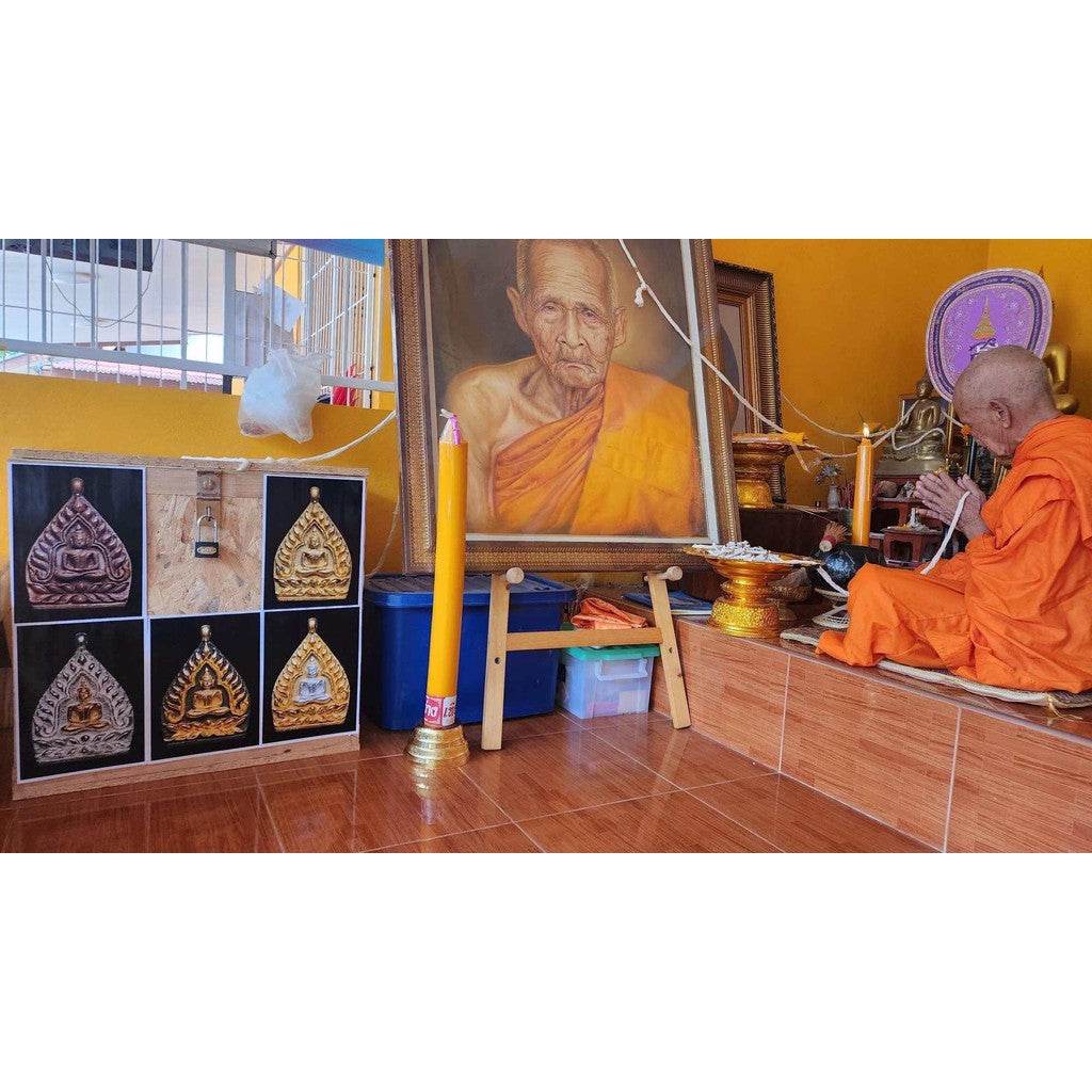 limited edition Thai lucky charm amulets displayed on altar while monk blesses them near portrait and candles