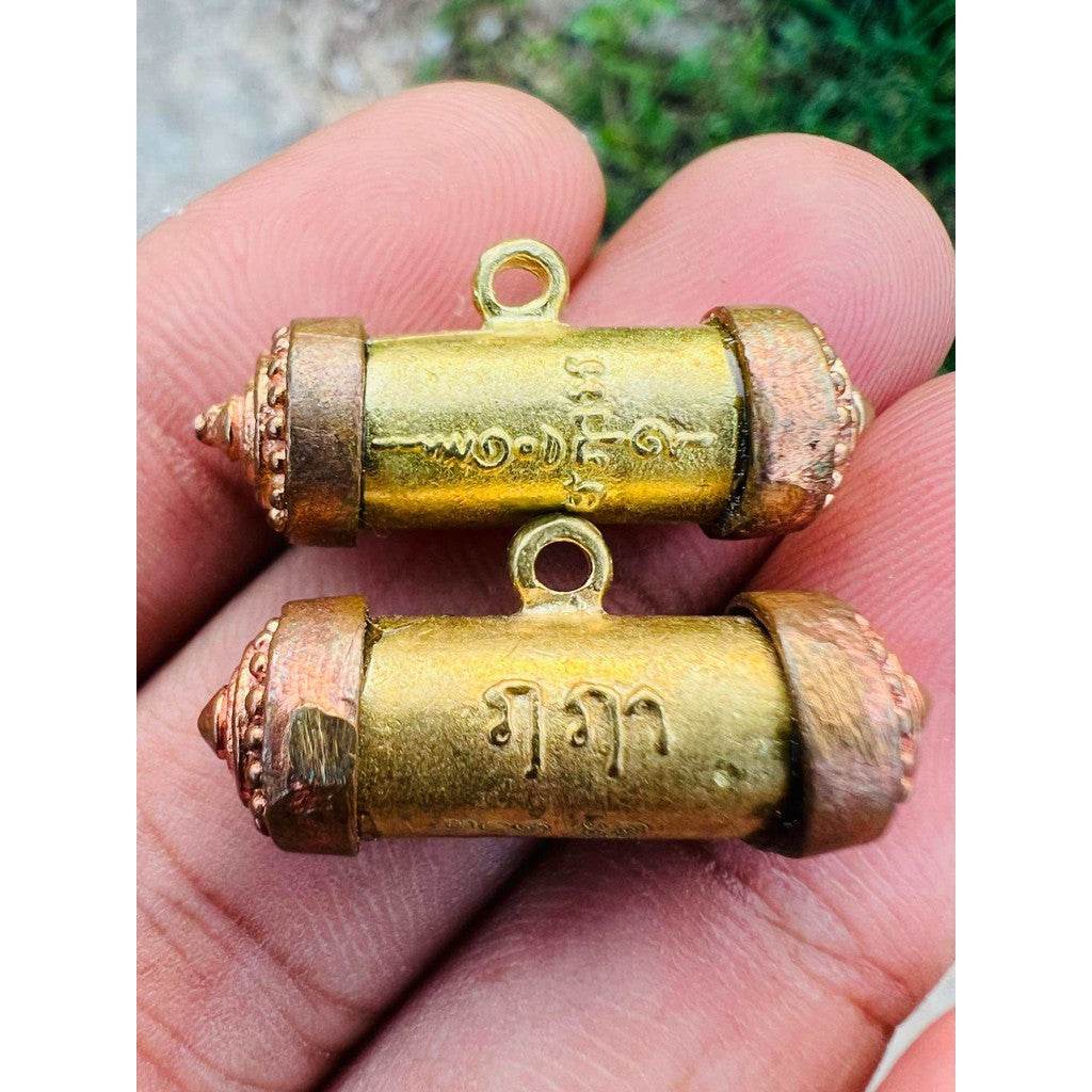 Mangkhang Ramruai amulet for prosperity gold tubular Thai amulets with copper ends held in hand