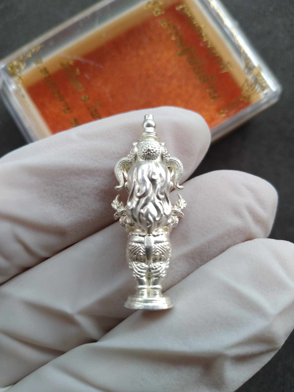 Silver amulet statue held in gloved hand Thai Blessing Co Naga Princess Goddess Setthi Phan Lan . Ornate detailing