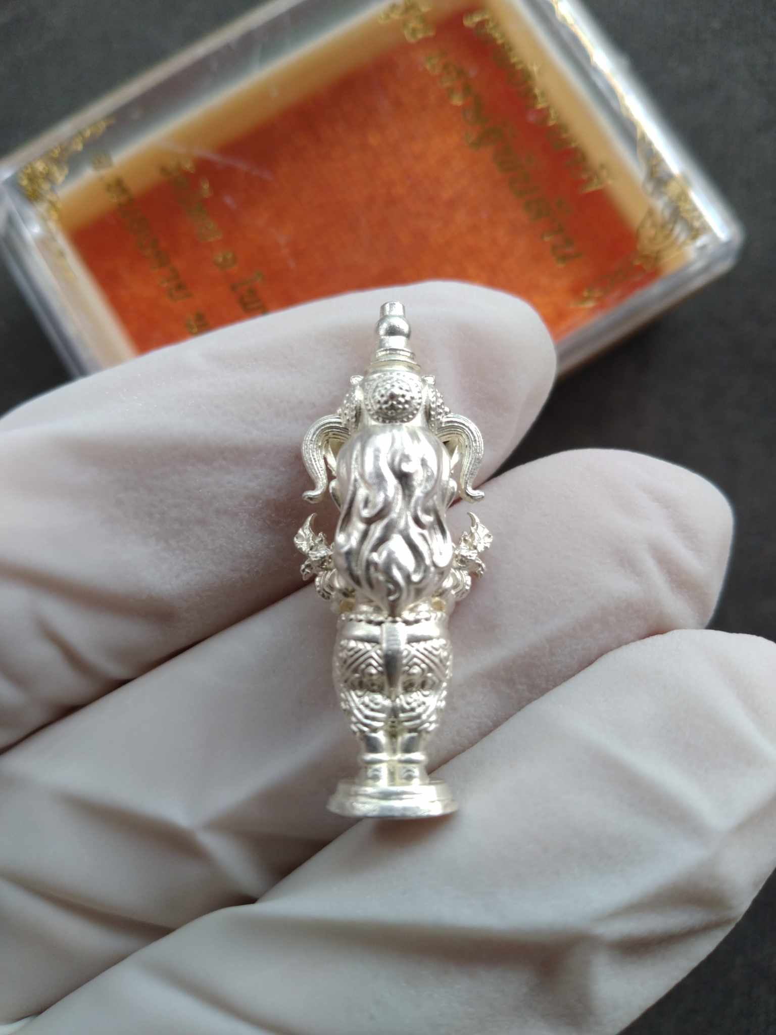Silver amulet statue held in gloved hand Thai Blessing Co Naga Princess Goddess Setthi Phan Lan . Ornate detailing