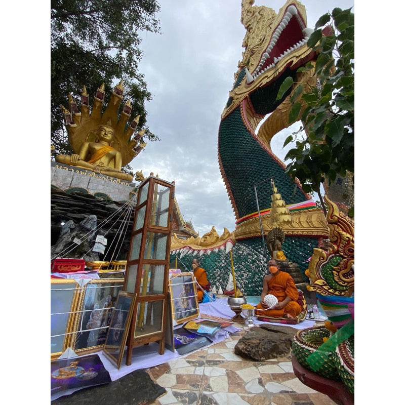 Thai temple monks with large green gold Naga statue and altar offering for Naga prosperity coin Thailand
