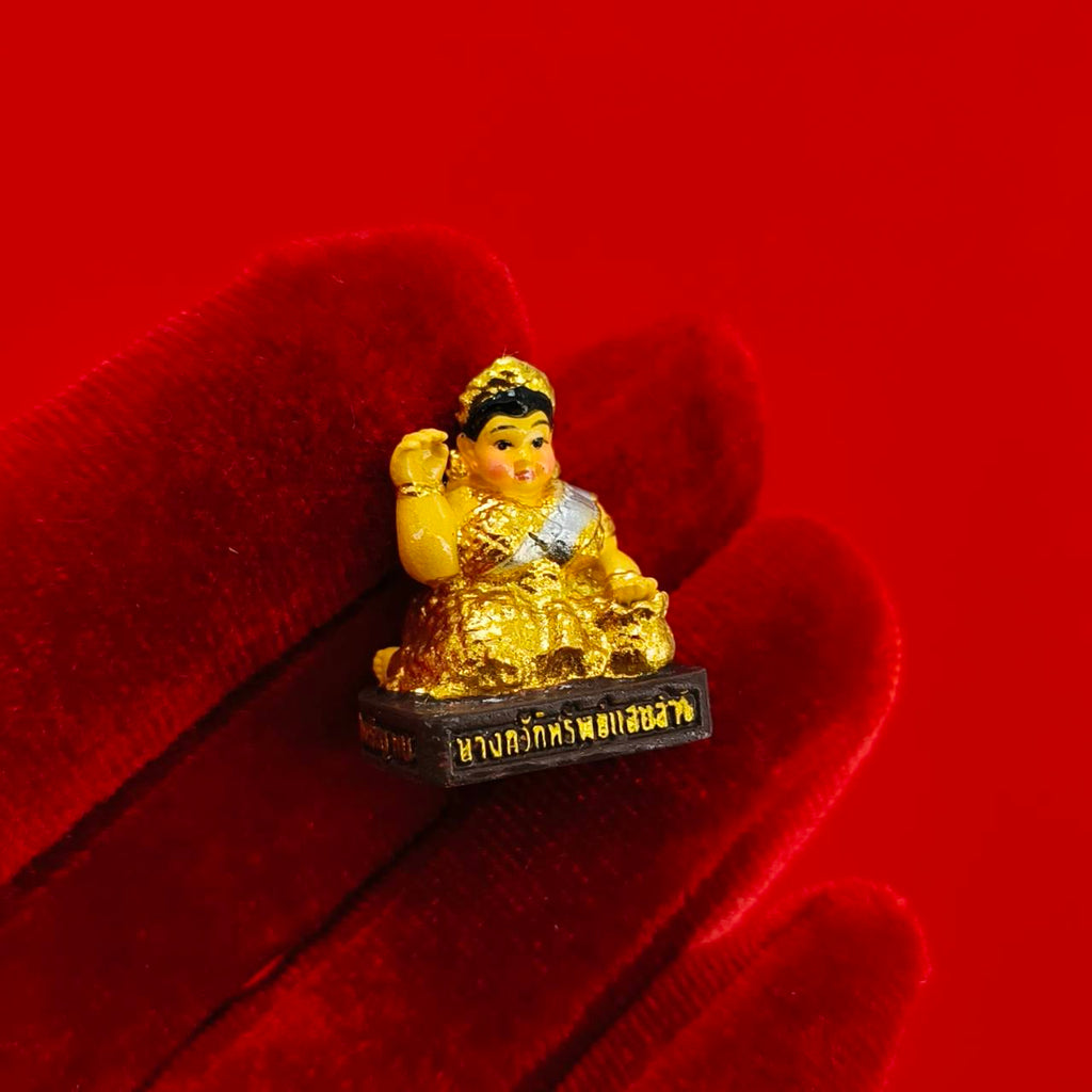 Thai Blessing Co Nang Kwak amulet for wealth miniature gold statue on black base held on red velvet glove