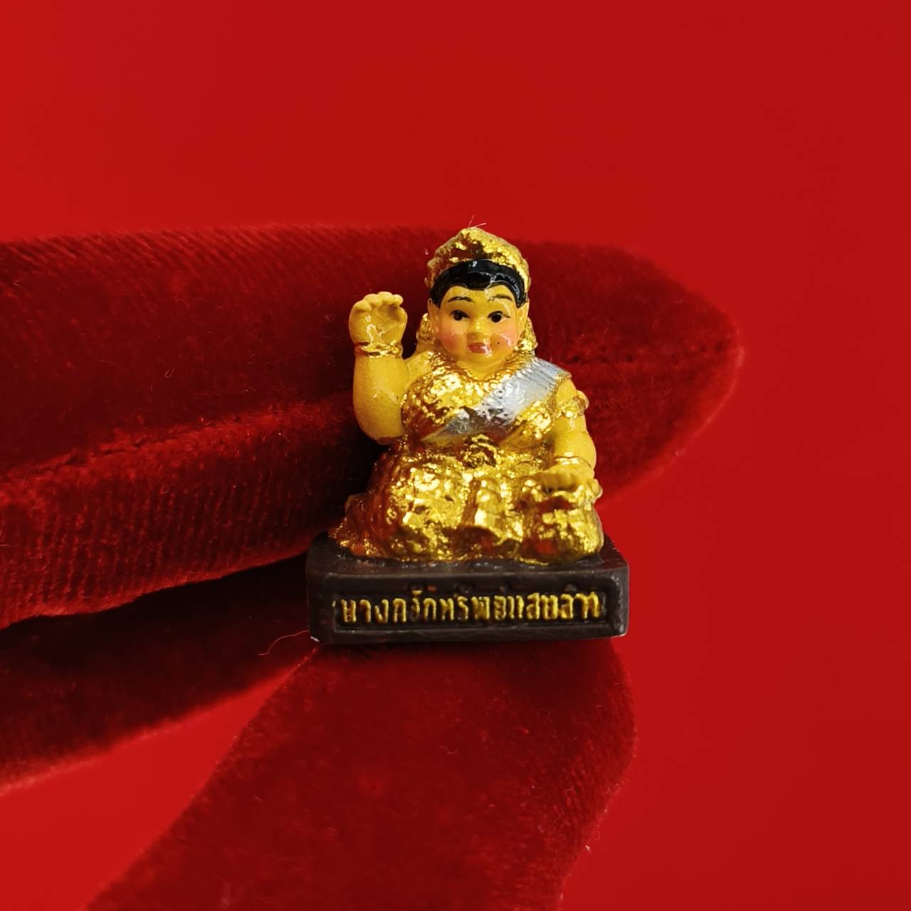 Thai Blessing Co Nang Kwak amulet for wealth small gold painted Thai prosperity figurine on red background