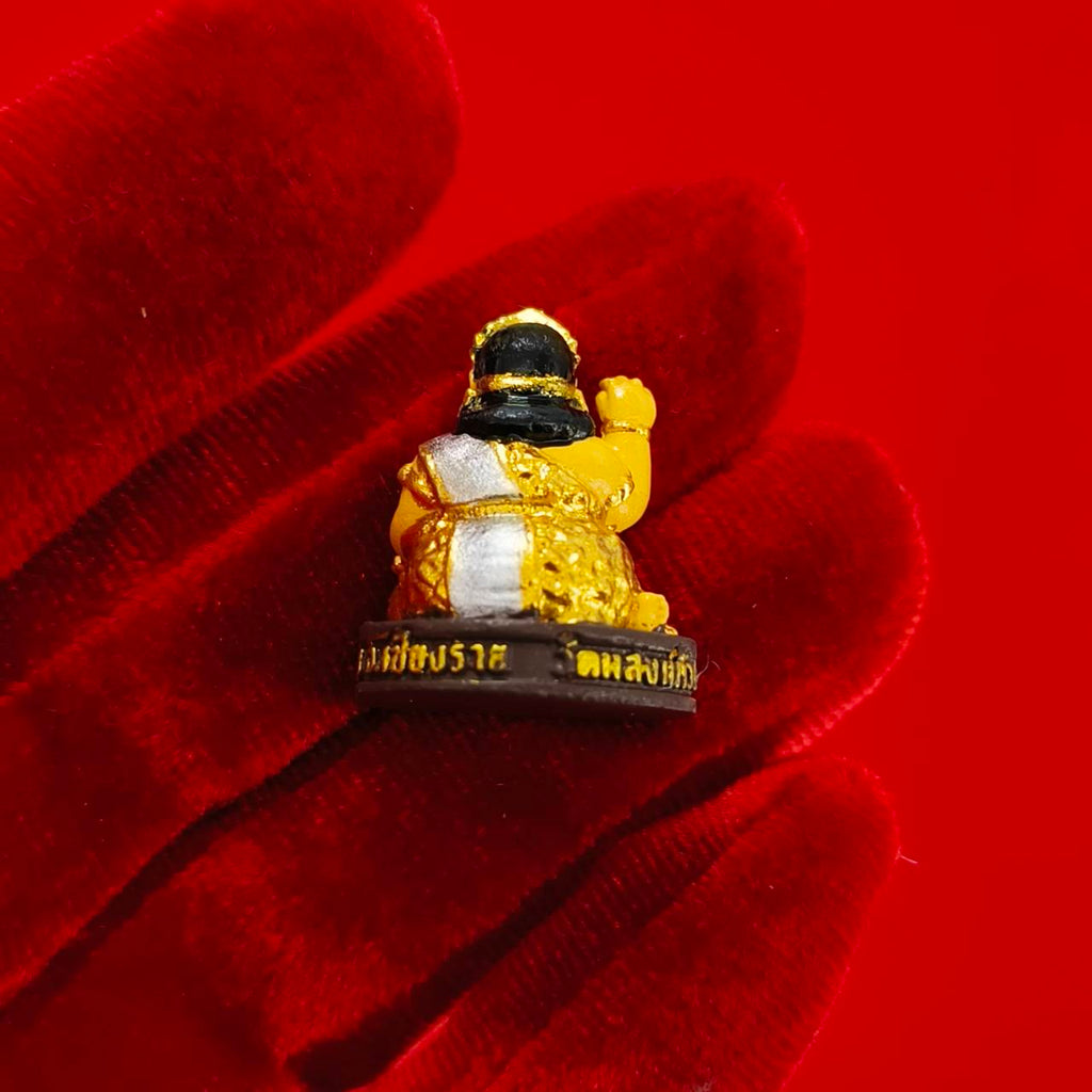 Thai Nang Kwak amulet for wealth small gold seated figurine on red velvet glove background