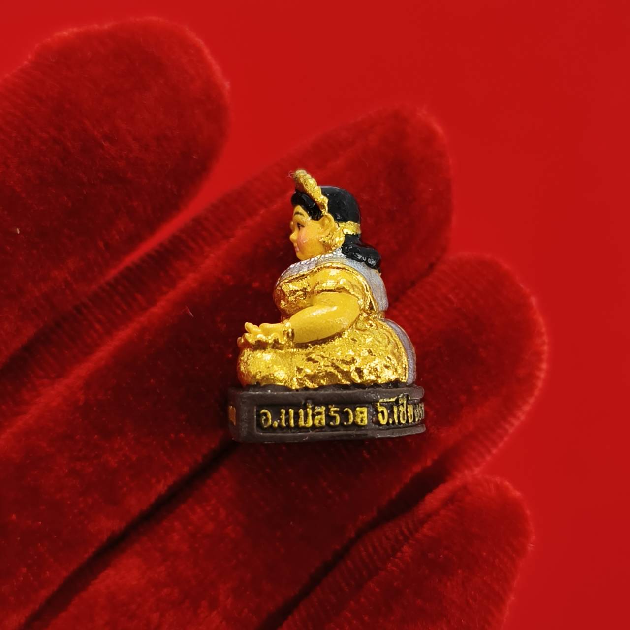 Nang Kwak amulet for wealth small gold painted Thai beckoning goddess figurine displayed on red velvet glove