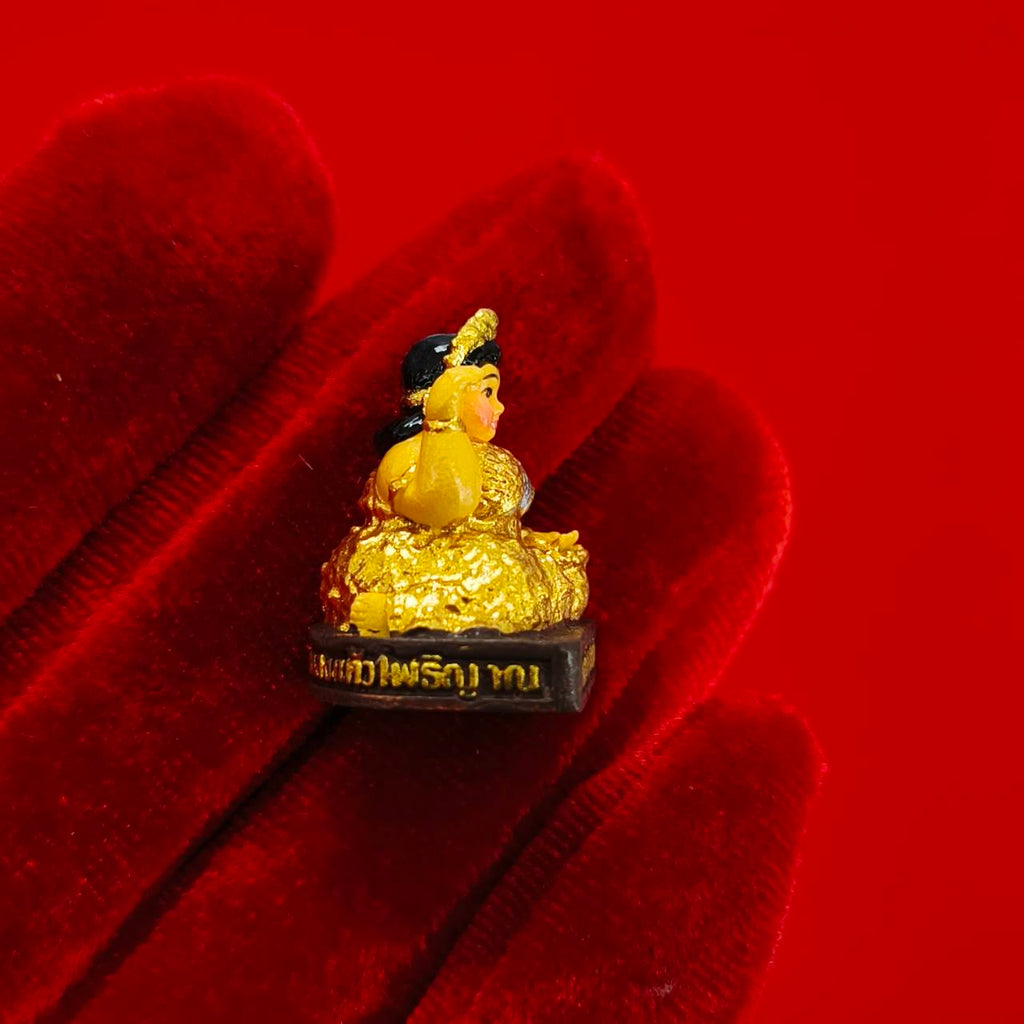Nang Kwak amulet for wealth gold figurine on pedestal with Thai script held on red velvet glove