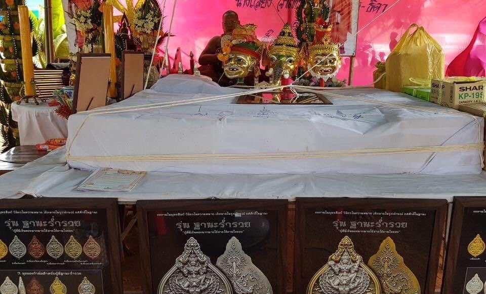 Thai Blessing Co display of Narai on Garuda amulet boxed pendants on cloth covered table at market