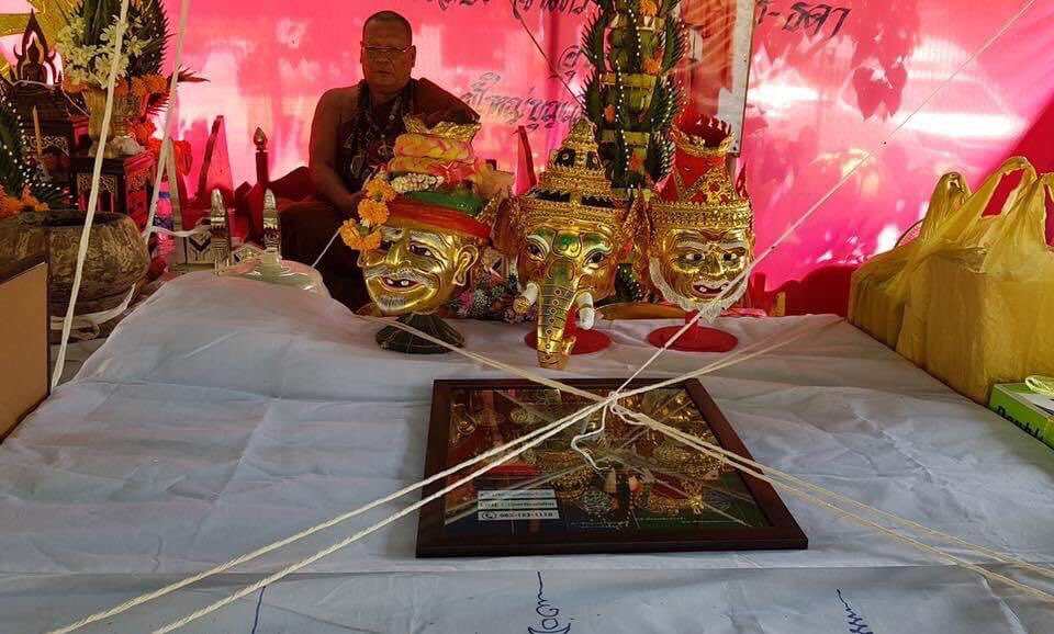Narai on Garuda amulet framed on ceremonial cloth with traditional Thai Khon masks and monk backdrop by Thai Blessing Co