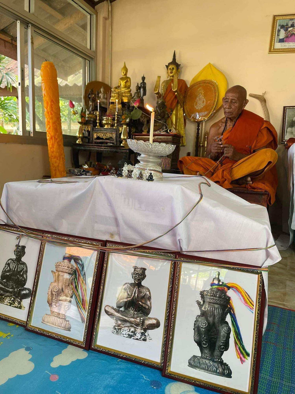 Norah Chatri Pi Takta amulet for protection. Thai monk at shrine with amulet statues framed photos and offerings