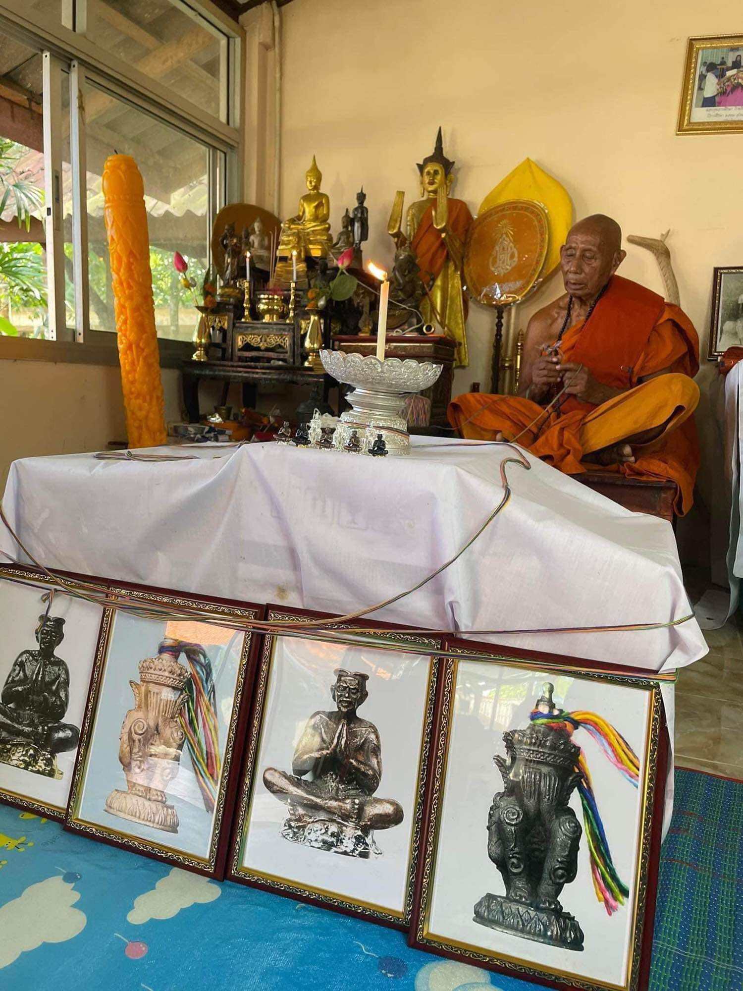 Norah Chatri Pi Takta amulet for protection. Thai monk at shrine with amulet statues framed photos and offerings