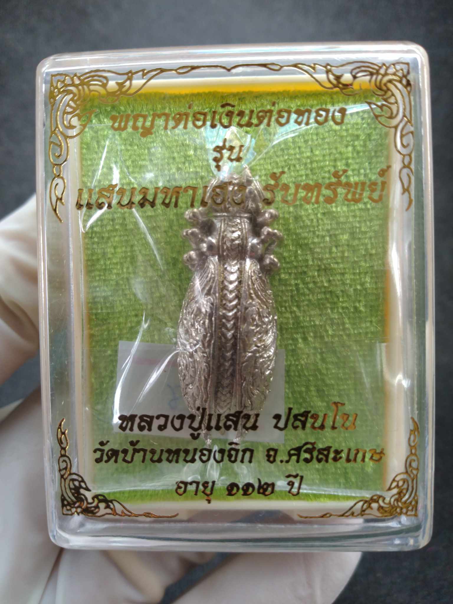 Phaya Tor Ngern Tor Thong amulet silver pendant in clear display box with green backing and gold Thai script