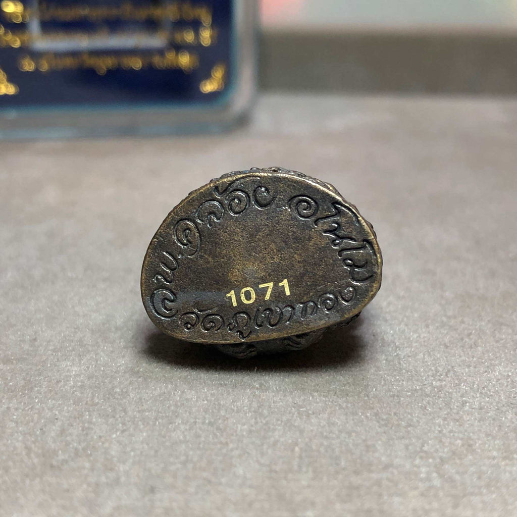 Close up base of aged bronze Phra Kring Srivichai amulet with engraved Thai script and gold serial 1071