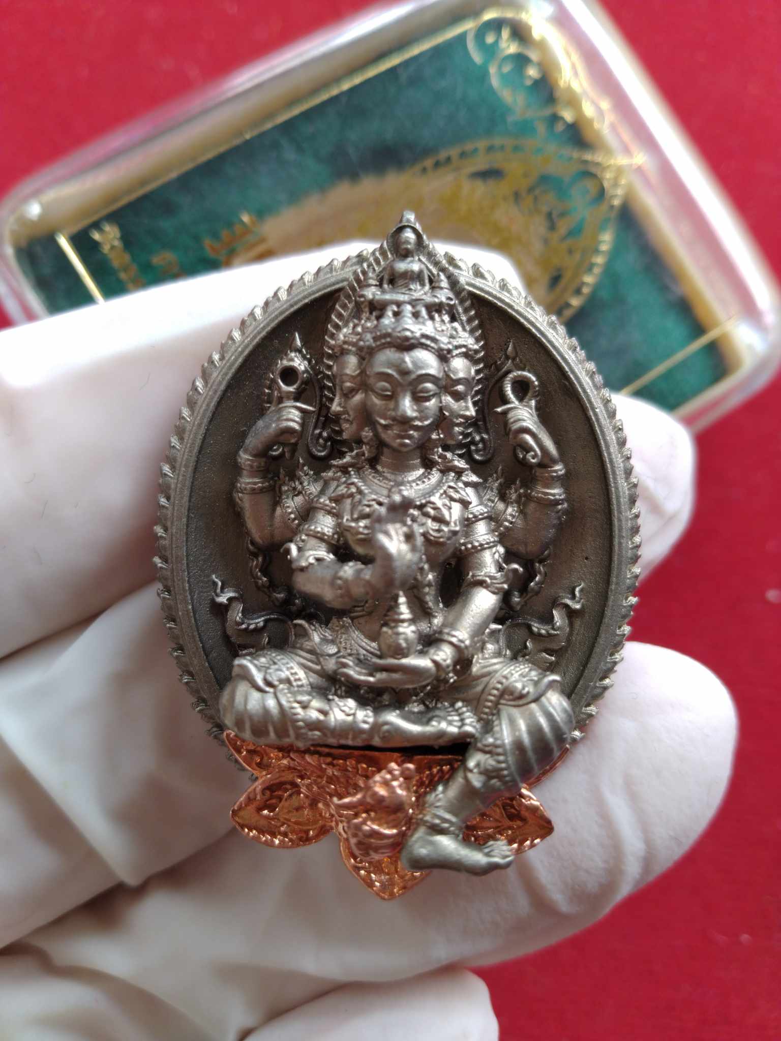 Phra Phrom Sethi amulet for wealth silver seated pendant with copper accents held in glove