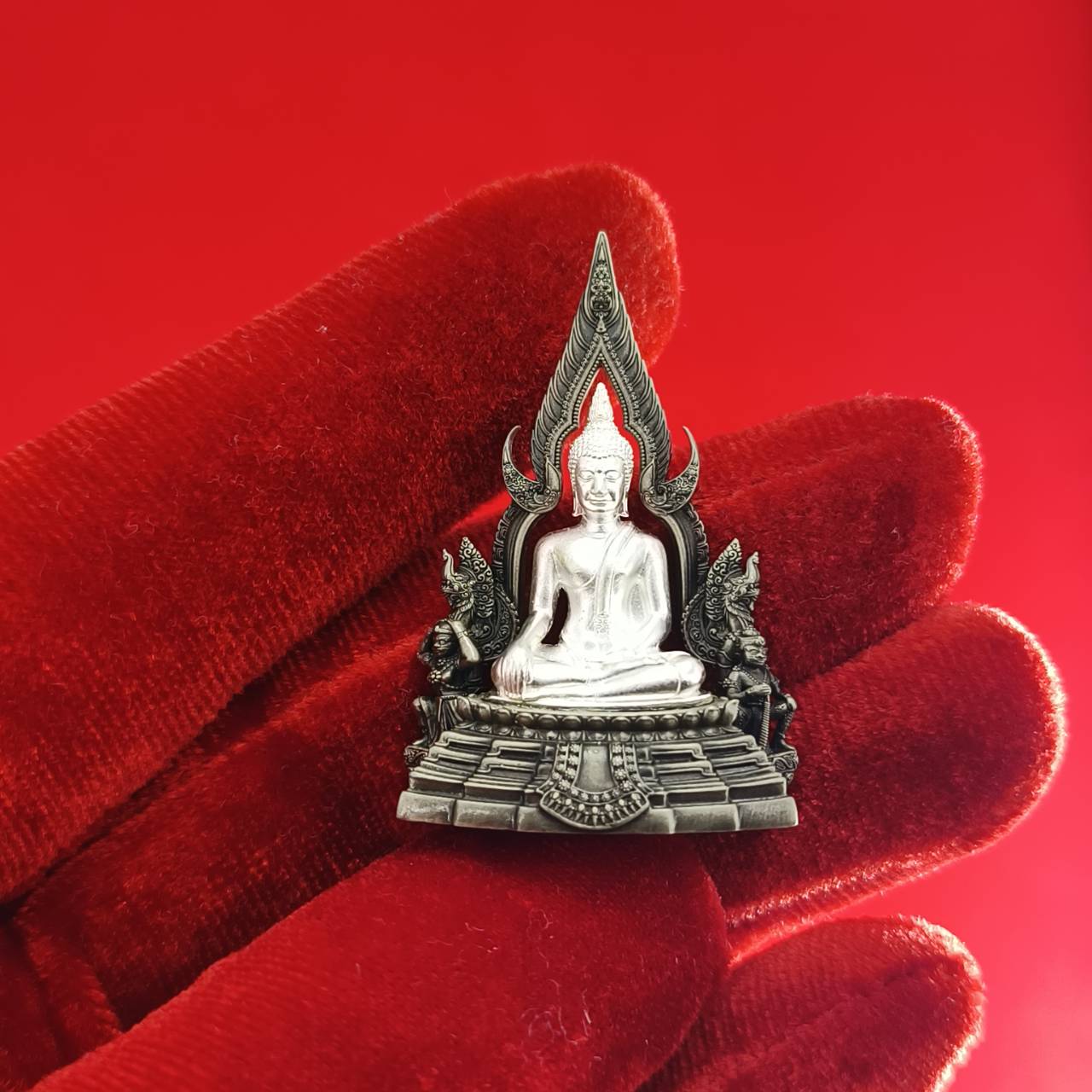 Phra Phuttha Chinnarat amulet silver Buddha pendant held on red velvet gloved hand for home shrine