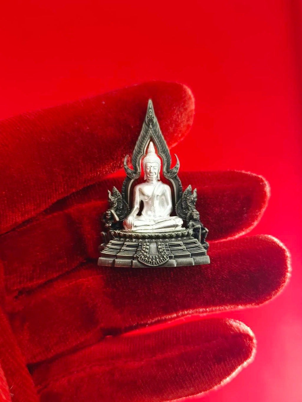 Phra Phuttha Chinnarat amulet silver devotional statue on ornate pedestal held in red velvet glove