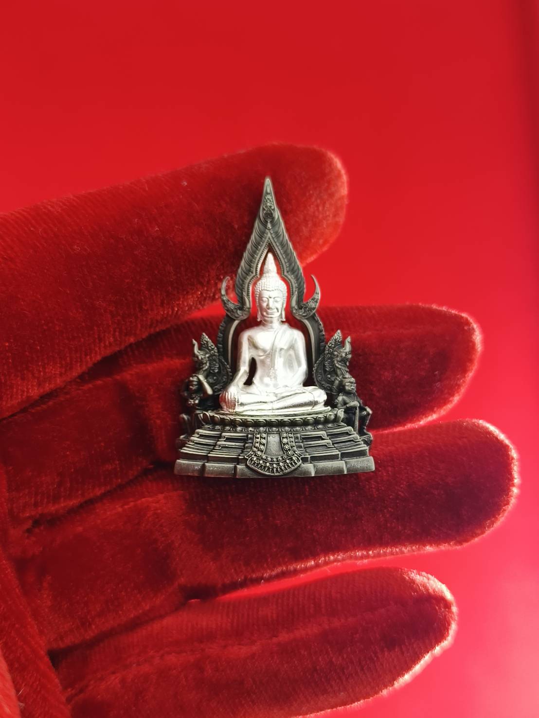 Phra Phuttha Chinnarat amulet silver devotional statue on ornate pedestal held in red velvet glove